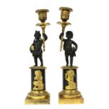 A pair of bronze parcel-gilt figural candlesticks,