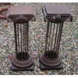 A pair of wrought iron column form stands of classical design,