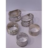 An unusual pair of heavy silver flat-sided napkin rings together with three other circular silver