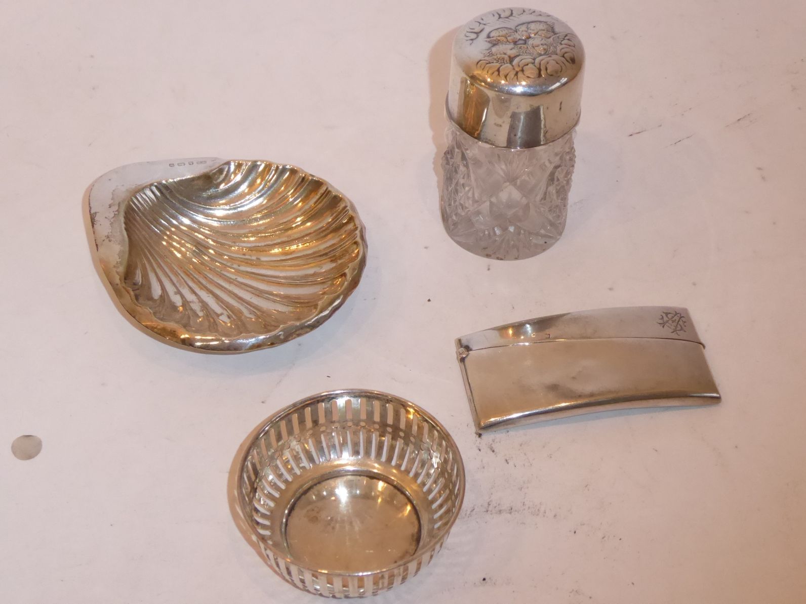 A silver group to include a scallop-shell-shaped butter dish, a silver mounted cut-glass scent