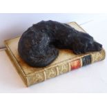 A paperweight modelled as a composition hound resting upon a 19th century style binding (18cm wide)