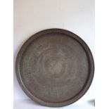 A large and heavy late 19th / early 20th century Islamic circular copper tray; dark patina and
