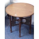 An early 20th century Liberty-style circular-topped walnut occasional table; dished top above a
