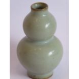 A Chinese Ming Dynasty double gourd form vase displaying a Ru/light celadon glaze, raised on short