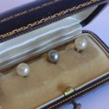 A cased set of three yellow-metal (marked) studs set with pearls