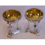 An unusual pair of circular salts with gilded bowls, each raised upon a stand with three cabriole