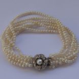 A six-strand pearl bracelet, the clasp flower-head shaped and centrally mounted with a large pearl