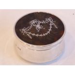 An early 20th century, hallmarked silver, circular dressing table box; the tortoiseshell and