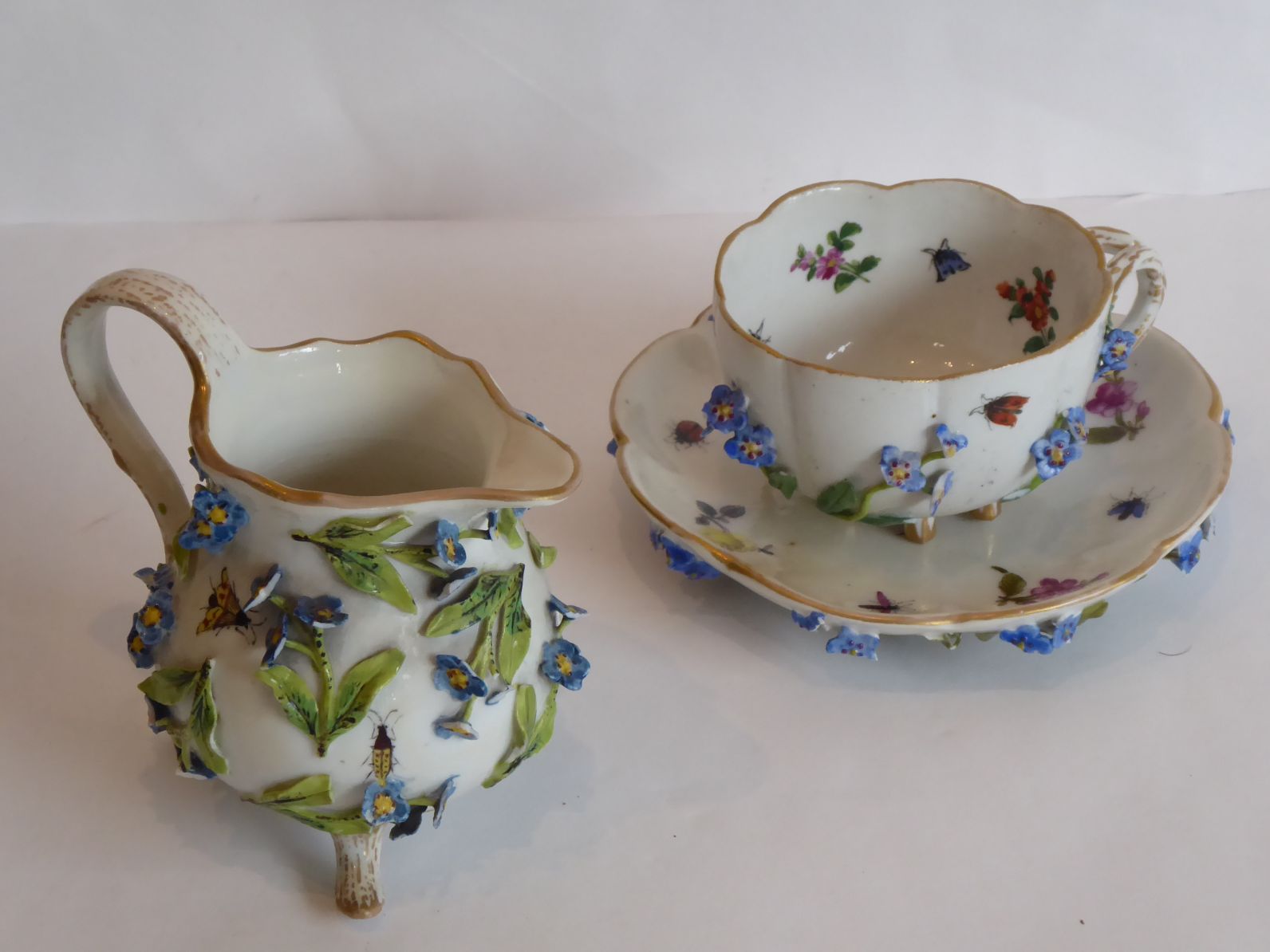 A late 19th century German porcelain (probably Meissen) cup and saucer; encrusted in relief with