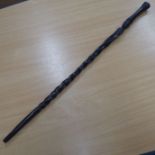 An African black heavy hardwood (probably ebony) walking cane, waisted handle above a carved