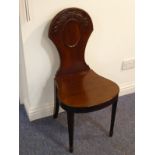 A late 18th century mahogany hall chair, the shaped back carved with laurel leaves in high relief,