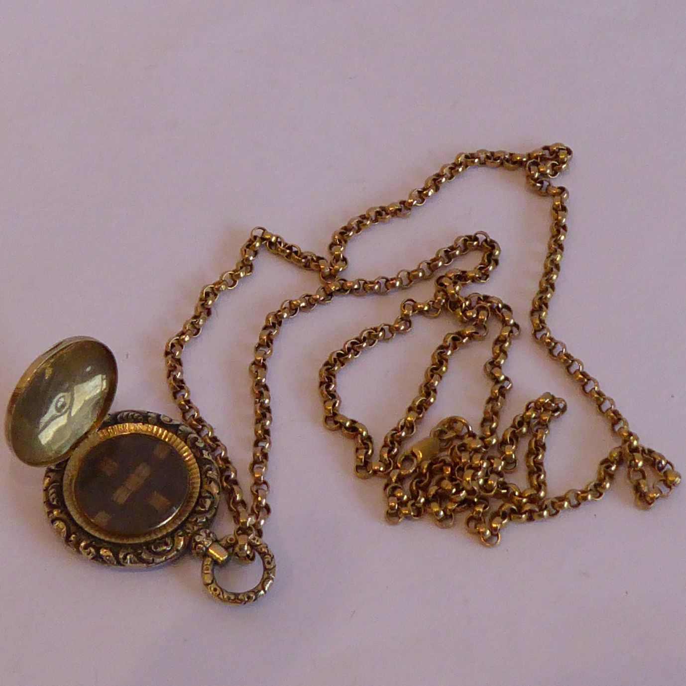 A 19th century yellow-metal circular mourning pendant containing a section of plaited dark and blond