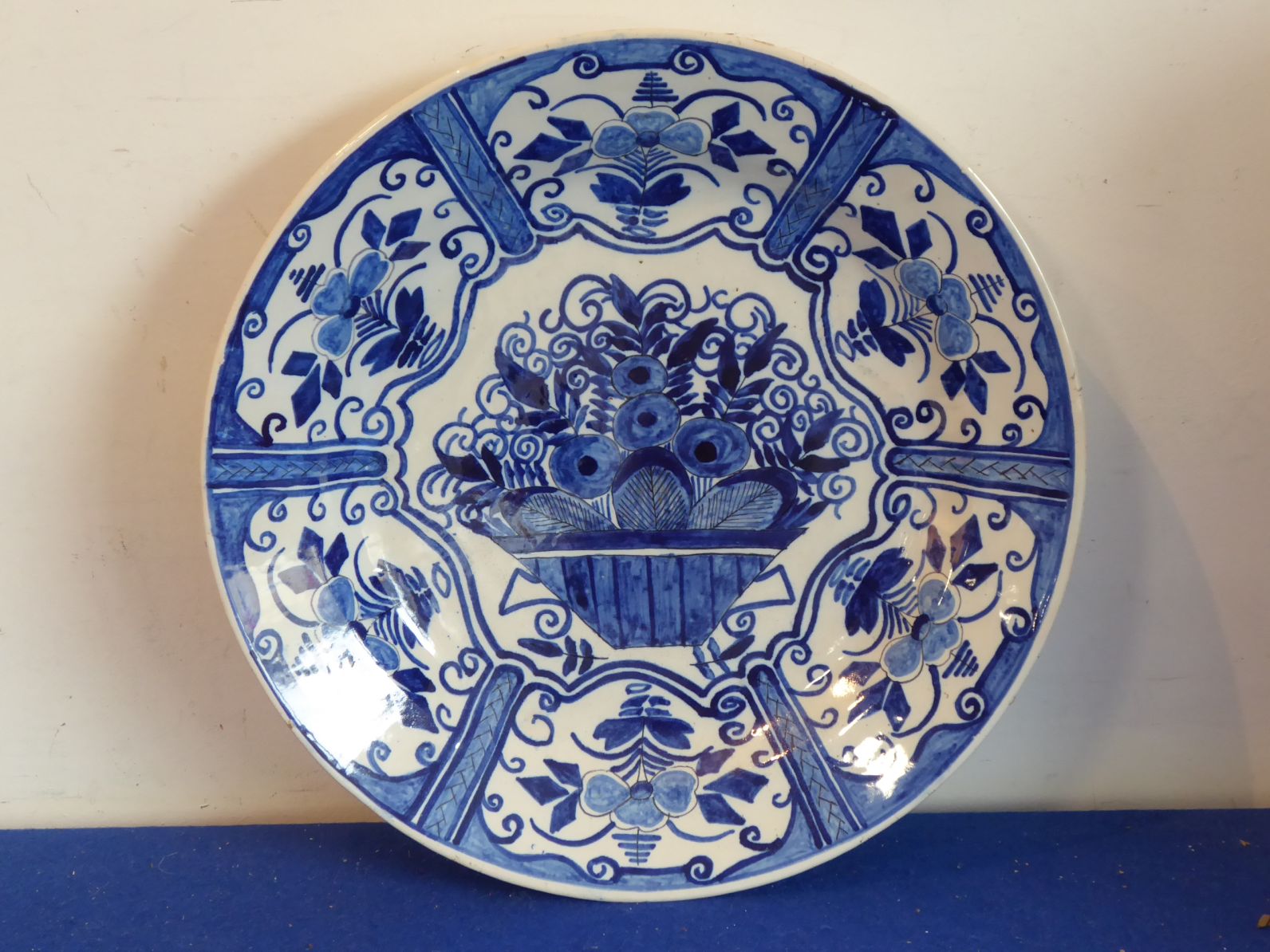 An 18th century Delftware charger hand-decorated in cobalt-blue with a central flower basket and six