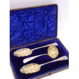 A cased berry spoon set comprising two berry spoons and a sugar sifter; gilded bowls and the 18th