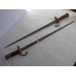 A pair of late 19th Century French bayonets each with brass and steel mounted wooden handle and with