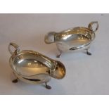 A pair of hallmarked silver sauce boats in the 18th century style; each with a scrolling handle