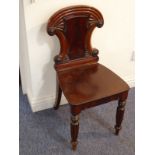 A late Regency/William IV period mahogany hall chair, the ornately carved back above a solid seat