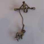 An unusual brooch (white metal and marked 935) set with a monkey sitting on a bar, to his right a