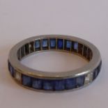 A heavy white-metal eternity ring set with sapphires interspersed with four diamonds at the N,E, S