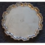 A heavy hallmarked silver salver; pie-crust edge, engraved armorial of a beehive and raised on three
