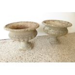 A pair of verdigrised stoneware garden urns; lobed lower bodies and upon square pedestal bases (