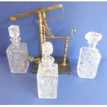 Three cut-crystal decanters together with a brass bottle pourer on a marble stand