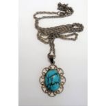 A silver-mounted pendant set with an oval cabochon turquoise stone within a pierced scrolling mount,