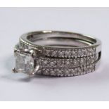 An 18-carat white-gold two-piece ring; 1/2 carat princess-cut diamond centre stone and many diamonds