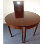 A George III extending mahogany oval dining table having one extra leaf, boxwood-strung frieze and