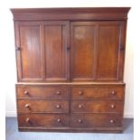 A large mid-19th century oak housekeeper's cupboard; outset cornice above panelled sliding doors and