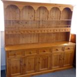 A pine dresser of very large proportions; the shelved superstructure with arches above shelves and