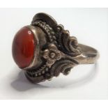 A white-metal ring set with an orange oval cabochon hardstone (boxed) (The cost of UK postage via