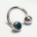 A boxed belly ring set with two cut light-blue stones (The cost of UK postage via Royal Mail Special