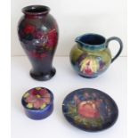 Four Moorcroft pieces comprising an early 20th century jug decorated in the leaf-and-berry