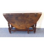 An 18th century oval-topped oak gateleg table; slender baluster-turned supports and single end-