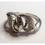 A white-metal ring marked 14K; central oval design flagged by two crescent shoulders set with