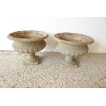 A pair of verdigrised stoneware garden urns each with lobed lower body and upon square pedestal base