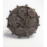 A 19th century circular metal brooch (probably silver) decorated with flowers and leaves (boxed) (