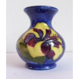 A small Moorcroft Pottery squat baluster-shaped vase, tube-lined and decorated with orchids,