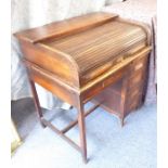 An early 20th century oak roll-top desk, the tambour top rolling back to reveal pigeon-holes above