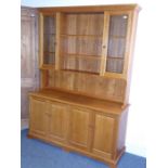 A good modern oak dresser unit; the outset cornice above central shelves flanked by two glazed doors