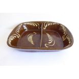 A large 19th century brown and white pottery slipware dish with central partition, small chip