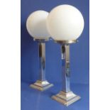 A pair of Art Deco-style chrome electric lamps with spherical glass shades
