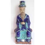 A late 19th/early 20th century Chinese pottery figure glazed in Tang-style; the dignitary seated