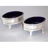 A pair of early 20th century boat-shaped silver-plated salts with blue-glass liners and engraved