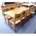 A pine kitchen-style trestle table on shaped supports, together with eight pine and rush-seated