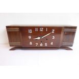 A French Art Deco-style walnut mantel clock with steel Arabic numerals, the movement striking on