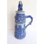A 19th century German blue faience pottery jug-and-cover in good condition; the cover with boy
