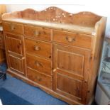 A pine dresser unit; wavy three-quarter galleried top above an arrangement of six drawers in T-