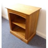 A modern pine bookcase; overhanging top above single shelf and raised on plinth base (65.5cm wide)